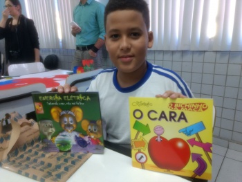 O aluno Robert Linhares mostra os livros que ganhou na EMEF Ronaldo Soares
