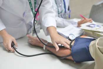 Profissional da saúde medindo pressão arterial em paciente do SUS